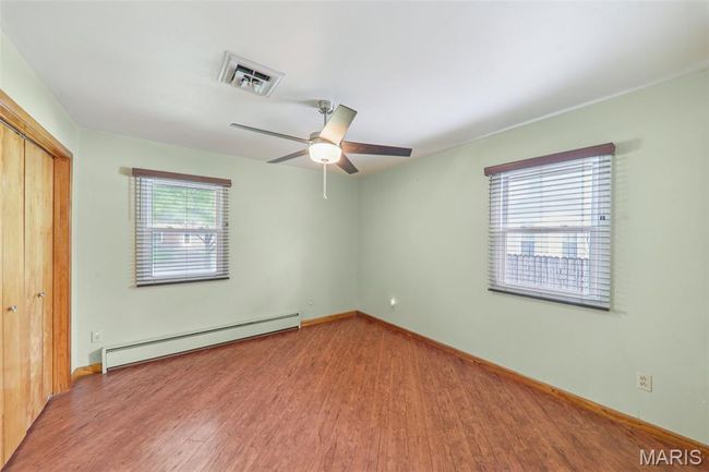 Unfurnished bedroom featuring a baseboard heating unit, wood finished floors, a closet, and ceiling fan | Image 21
