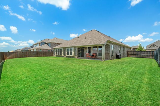 Rear view of house with a fenced backyard, brick siding, a patio area, and roof with shingles | Image 25