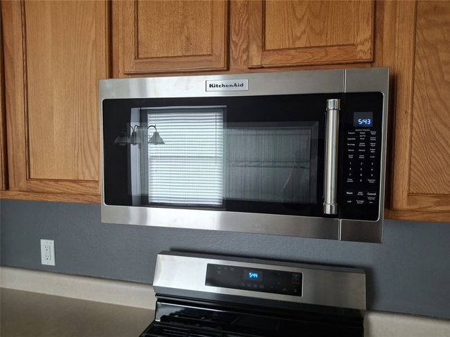 Kitchen view of stainless steel microwave, range, and brown cabinets | Image 19
