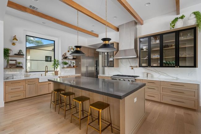 Kitchen featuring visible vents, stainless steel appliances, wall chimney range hood, open shelves, and a sink | Image 12
