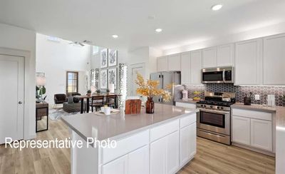 Kitchen with appliances with stainless steel finishes, backsplash, light wood-type flooring, white cabinets, and a center island | Image 3