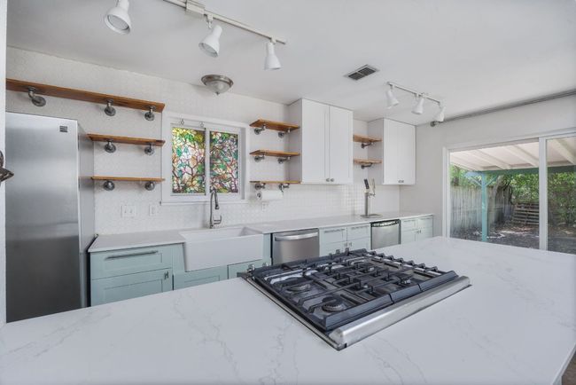 Kitchen featuring open shelves, appliances with stainless steel finishes, track lighting, backsplash, and white cabinetry | Image 8