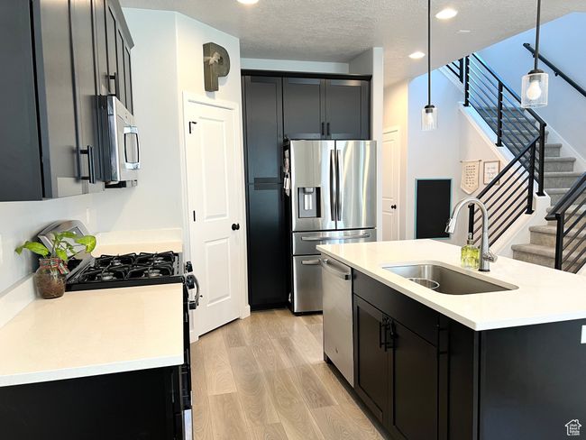 Beautiful kitchen, featuring an island with a sink that has a water filter, and a staircase to the second floor. | Image 6