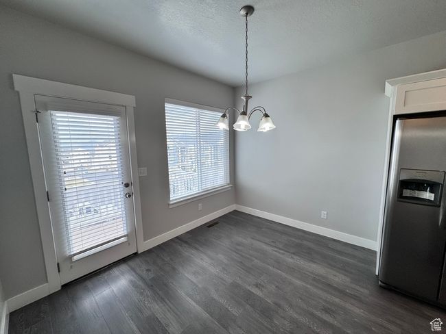 Unfurnished dining area with baseboards, a chandelier, and dark wood finished floors | Image 9