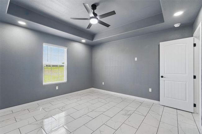 Unfurnished room featuring tile finish floor, a raised ceiling, a ceiling fan, and baseboards | Image 23