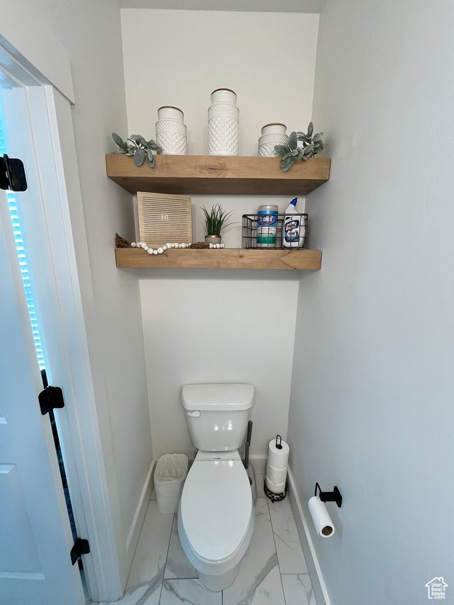 Bathroom featuring marble look tile flooring, toilet, and baseboards | Image 10