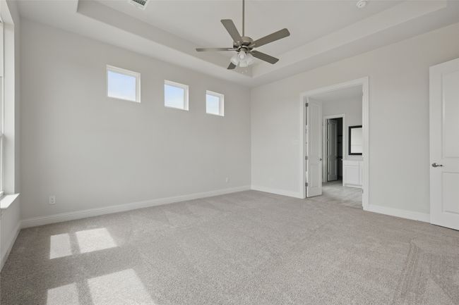 Unfurnished room with a tray ceiling, light colored carpet, ceiling fan, and baseboards | Image 15