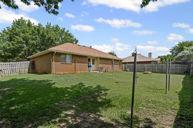Rear view of property with brick siding, a fenced backyard, and roof with shingles | Image 23