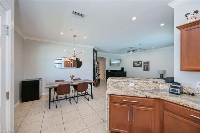 Kitchen featuring visible vents, a peninsula, light tile patterned flooring, arched walkways, and ceiling fan with notable chandelier | Image 10