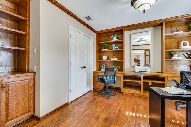 Office with built in shelves, light wood-style flooring, visible vents, baseboards, and crown molding | Image 7
