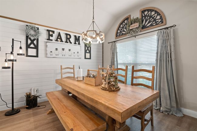 Dining space featuring wood finished floors, a chandelier, vaulted ceiling, and wooden walls | Image 5