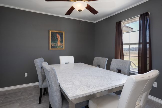 Dining space featuring baseboards, ornamental molding, wood finished floors, and ceiling fan | Image 9