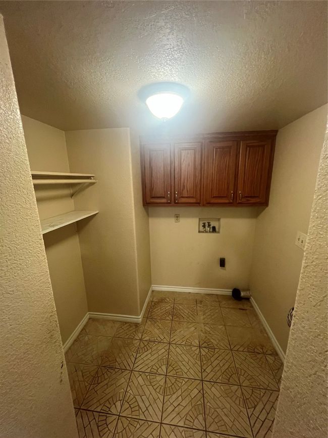 Laundry room featuring washer hookup, hookup for an electric dryer, a textured ceiling, light tile patterned flooring, and a textured wall | Image 18