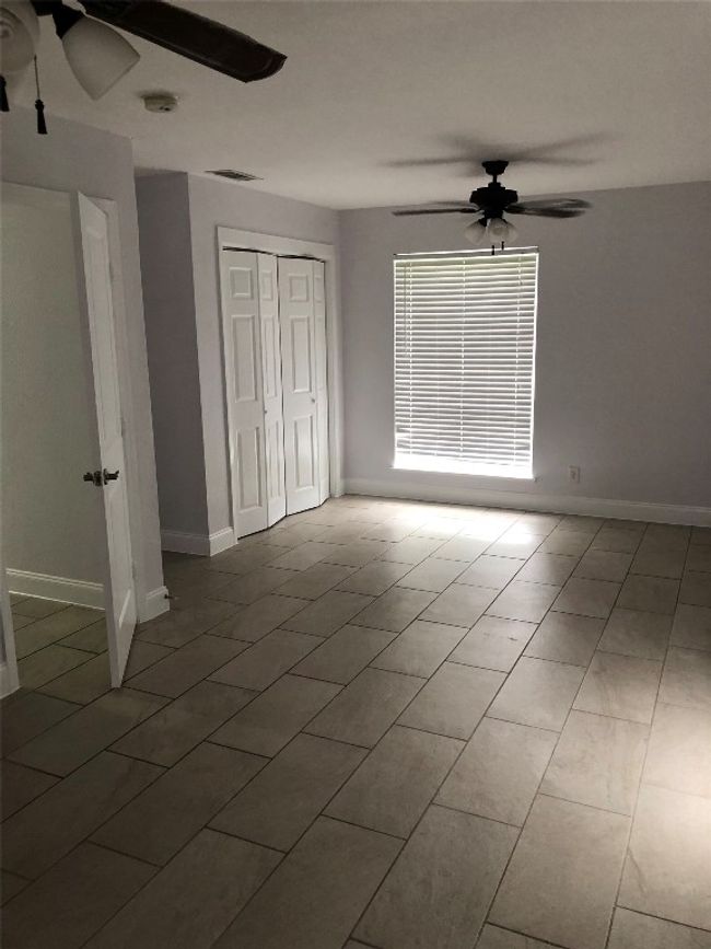 Unfurnished bedroom with tile patterned flooring, a closet, and a ceiling fan | Image 12