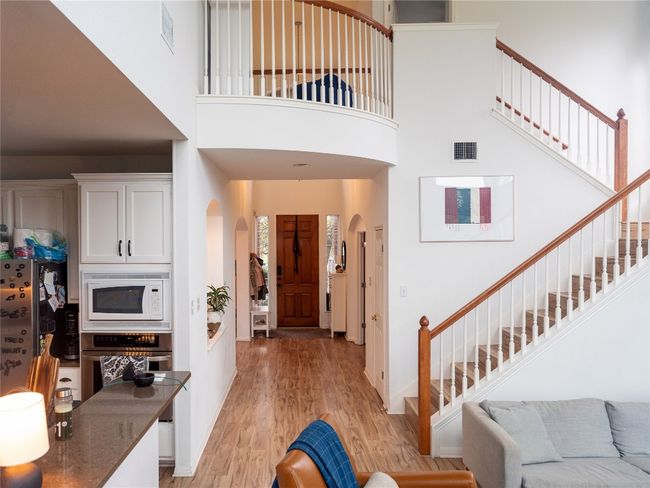 Entrance foyer with arched walkways, stairway, light wood finished floors, and a high ceiling | Image 24