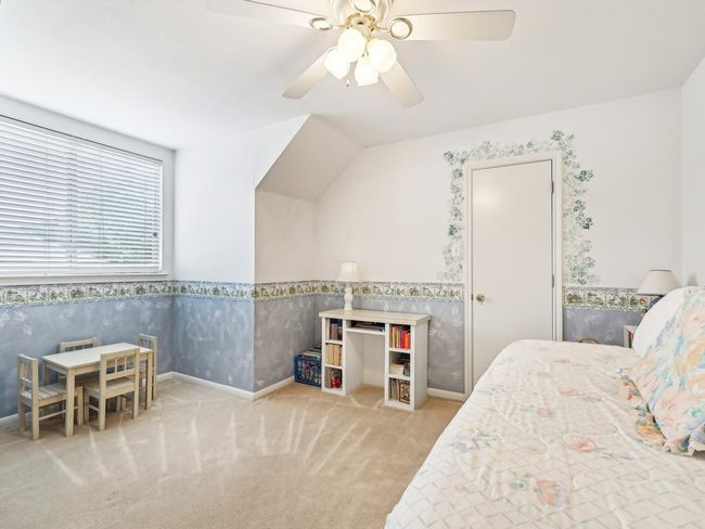Carpeted bedroom with wallpapered walls, wainscoting, baseboards, ceiling fan, and lofted ceiling | Image 23