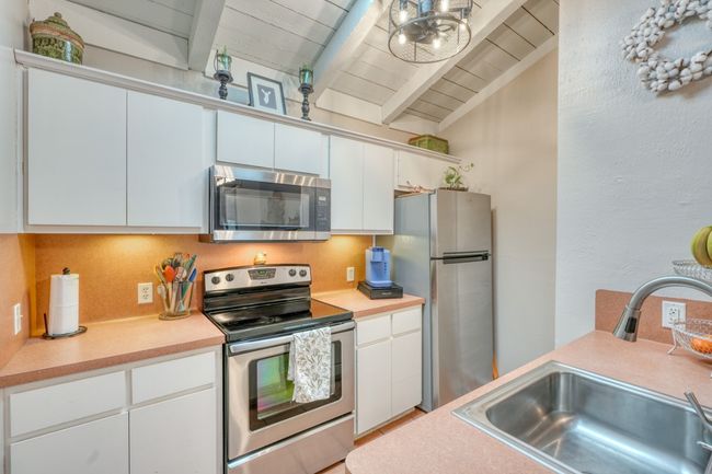 Kitchen featuring a sink, light countertops, white cabinets, and stainless steel appliances upper unit | Image 21