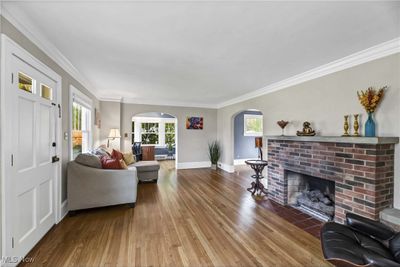 Living room featuring a brick fireplace, ornamental molding, and hardwood / wood-style floors | Image 2