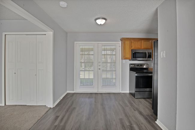 Kitchen featuring baseboards, stainless steel appliances, dark wood-type flooring, french doors, and a textured ceiling | Image 5