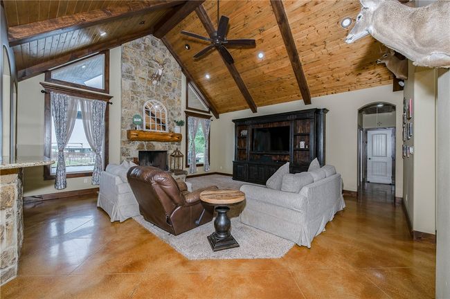 Living area with a ceiling fan, baseboards, wood ceiling, a fireplace, and high vaulted ceiling | Image 10