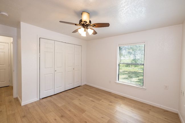 Unfurnished bedroom with a closet, baseboards, ceiling fan, and light wood-style floors | Image 18