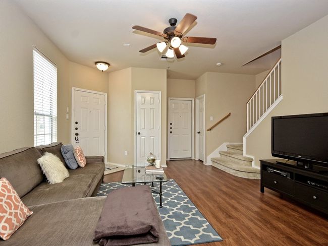Living room with wood finished floors, a ceiling fan, and stairway | Image 5