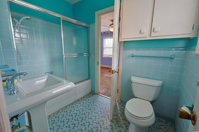 Full bath featuring tile patterned floors, tile walls, enclosed tub / shower combo, and a ceiling fan | Image 13