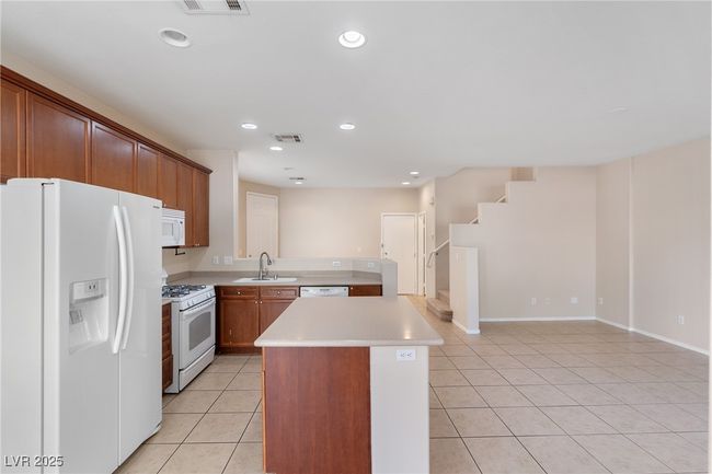 Kitchen featuring white appliances, light tile patterned floors, light countertops, a center island, and recessed lighting | Image 4