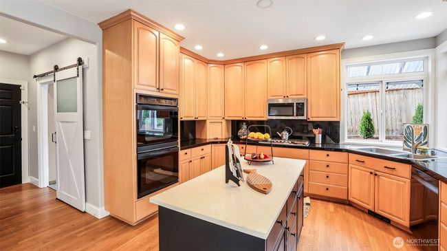 Both the pantry and laundry room feature stylish barn slider doors, conveniently located beside the kitchen, which boasts a double oven and tall cabinetry for added storage and functionality | Image 22