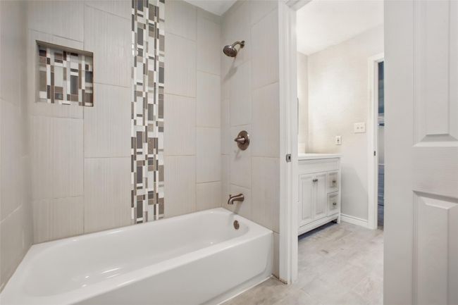 Updated with custom tile backsplash and cohesive lighting—every detail of this shower/tub combo feels elevated. | Image 28