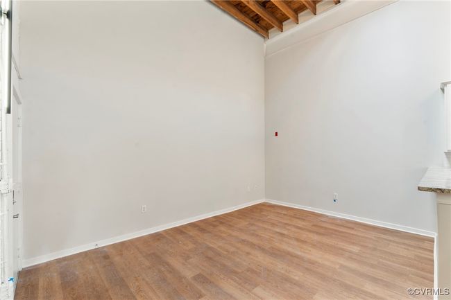 Spare room featuring baseboards, light wood finished floors, and beam ceiling | Image 9