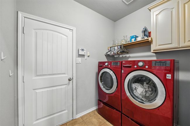 Washroom featuring independent washer and dryer, light tile patterned floors, and cabinet space | Image 23