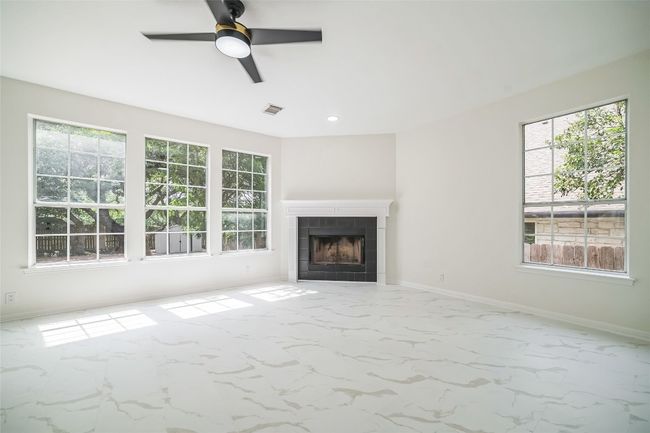 Unfurnished living room featuring ceiling fan, a fireplace, marble finish flooring, recessed lighting, and baseboards | Image 31