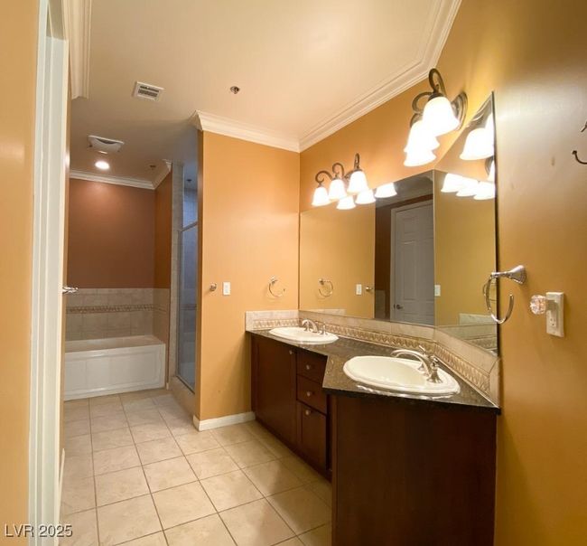 Bathroom featuring tile patterned floors, crown molding, double vanity, a bath, and an enclosed shower | Image 17