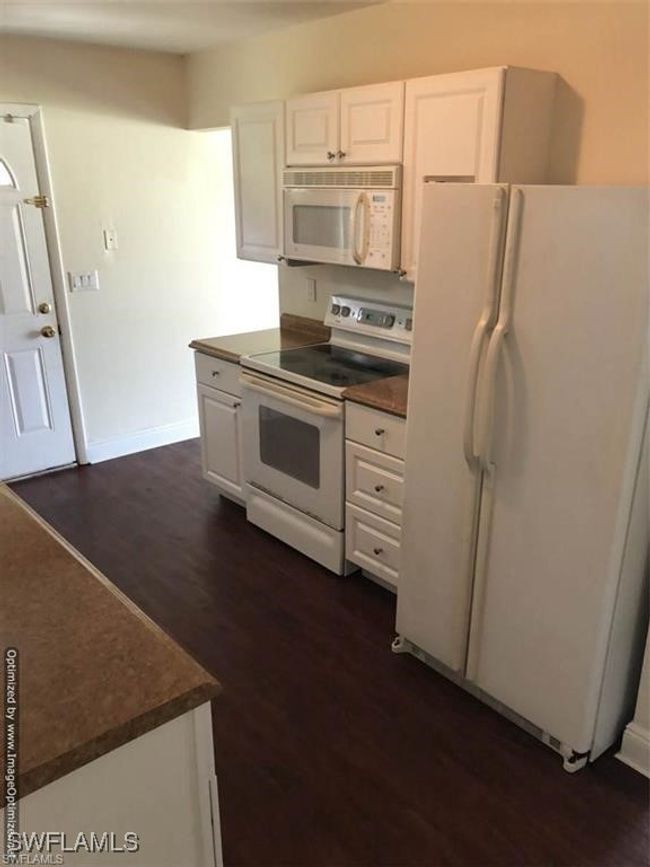 Kitchen featuring dark wood-type flooring, white appliances, and white cabinets | Image 5