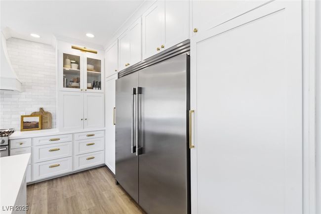 Kitchen with white cabinetry, light wood-style floors, light countertops, and stainless steel built in fridge | Image 14