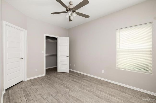 Unfurnished bedroom with light wood-type flooring, a walk in closet, a ceiling fan, and a closet | Image 10