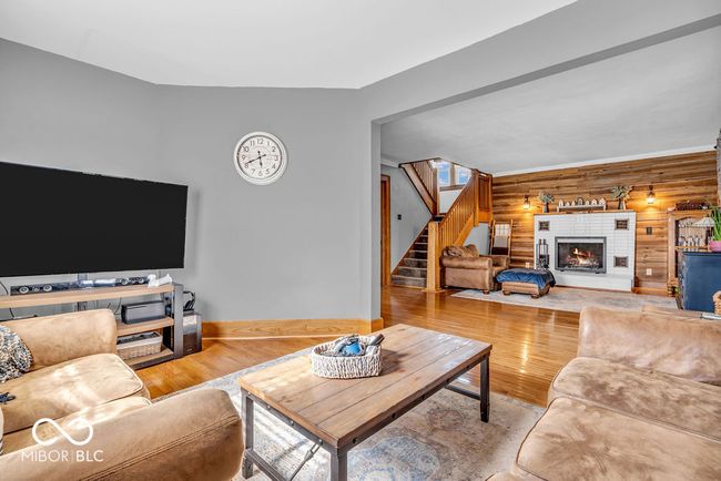 living area featuring stairway, wood finished floors, a fireplace, and wood walls | Image 15