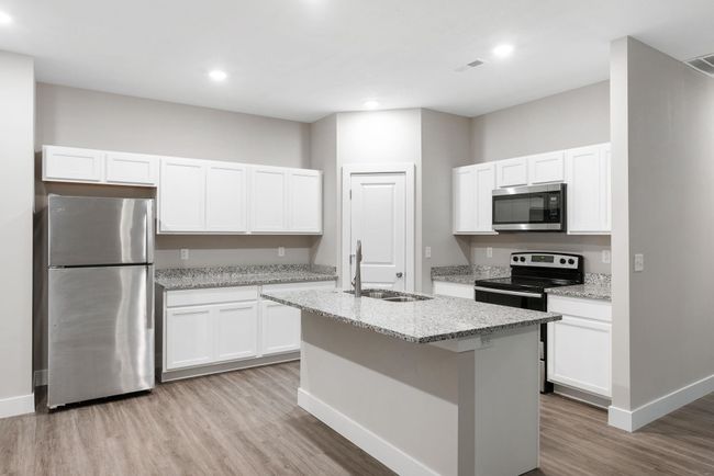 Kitchen with appliances with stainless steel finishes, a sink, light wood-type flooring, white cabinetry, and recessed lighting | Image 12