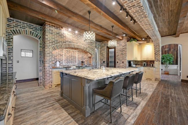 Kitchen featuring baseboards, light wood-style flooring, cream cabinets, a kitchen island with sink, and beamed ceiling | Image 18