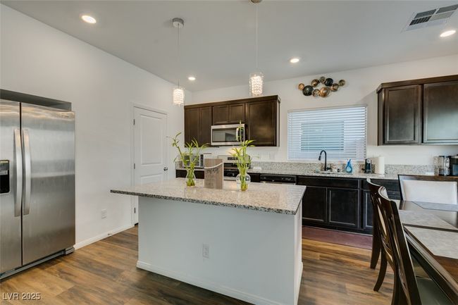 Kitchen featuring light stone counters, a sink, stainless steel appliances, visible vents, and dark wood-type flooring | Image 6