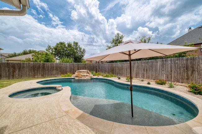 View of pool featuring a fenced backyard and a pool with connected hot tub | Image 32