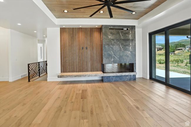 Unfurnished living room with ceiling fan, hardwood / wood-style flooring, recessed lighting, a high end fireplace, and wooden ceiling | Image 6