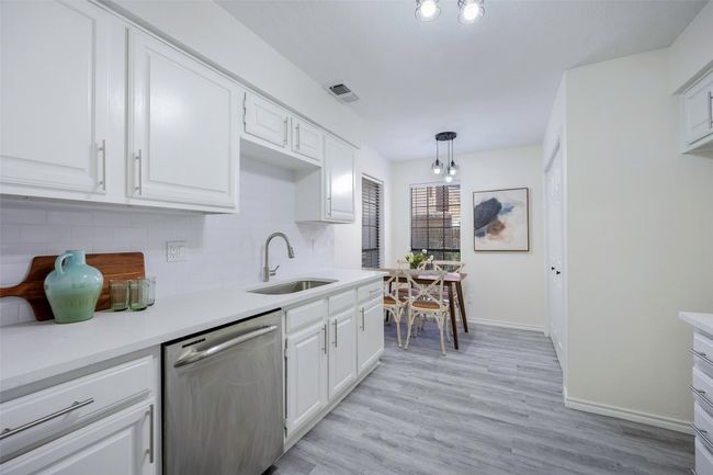 Kitchen with visible vents, a sink, white cabinets, dishwasher, and backsplash | Image 11