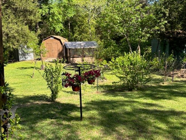 View of yard featuring a storage shed and an outdoor structure in the beautiful landscaped yard and garden | Image 13