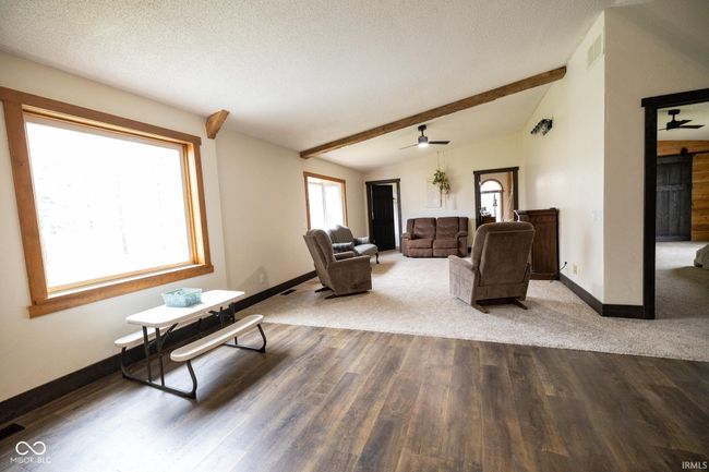 living room featuring lofted ceiling with beams, wood finished floors, ceiling fan, and baseboards | Image 4
