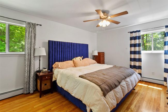Bedroom with a baseboard radiator, wood finished floors, and a ceiling fan | Image 8