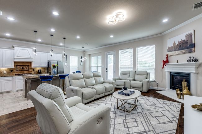 Living room with ornamental molding, a glass covered fireplace, recessed lighting, and wood finished floors | Image 6