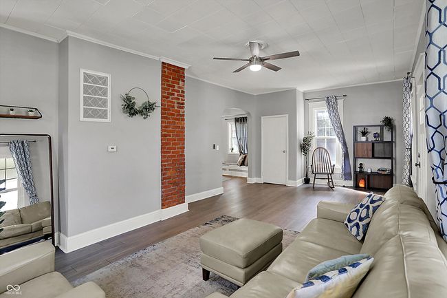 living area with arched walkways, wood finished floors, crown molding, and ceiling fan | Image 9