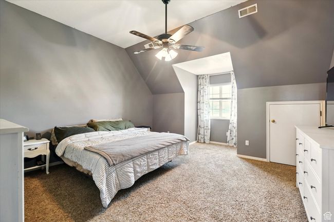 Bedroom featuring vaulted ceiling, light carpet, baseboards, and a ceiling fan | Image 14